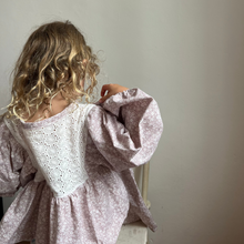 Load image into Gallery viewer, Child wearing a light purple top with lace details, standing against a plain wall.