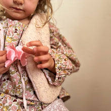 Load image into Gallery viewer, Child wearing a floral outfit holding a pink bow against a neutral background