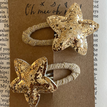 Load image into Gallery viewer, Gold star-shaped hair clips on a textured brown card with text background
