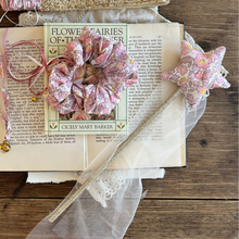 Load image into Gallery viewer, Decorative setup with an open book, flowers, a tiara, and ribbons on a wooden surface.