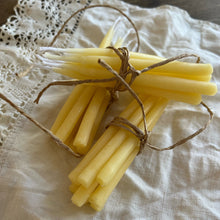 Load image into Gallery viewer, Bundled yellow candles tied with twine on a textured white fabric background