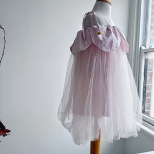 Mannequin wearing a pink dress with a pink tulle skirt in a room with a window.