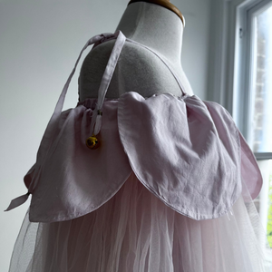 Detail of mannequin wearing a light pink dress with a petals in a room with a window.