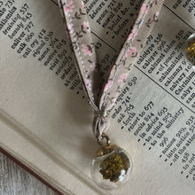 Load image into Gallery viewer, Decorative ribbon with a small glass pendant on an open book