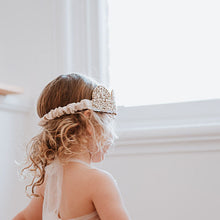 Load image into Gallery viewer, Child in a gold sequin dress with a white tulle skirt standing in a room with white walls and wooden floor.