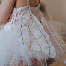 Load image into Gallery viewer, Child wearing a white dress with gold accents and a tutu, standing on a wooden floor.