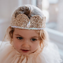 Load image into Gallery viewer, Child wearing a sparkling gold crown with a blurred background
