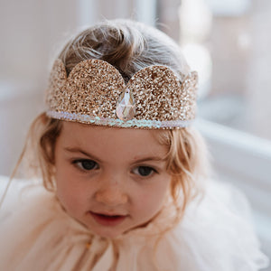 Child wearing a sparkling gold crown with a blurred background