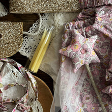 Load image into Gallery viewer, Decorative items including  star-shaped object, and floral fabric on a wooden surface.